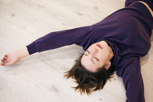 Woman lies on the floor with her eyes closed in sportswear