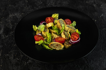 traditional German maultaschen, baked with purple onion, fresh tomatoes and young salad on a dark background