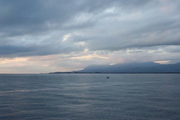 Cloudy day at sea and dark rain clouds on the background of the island