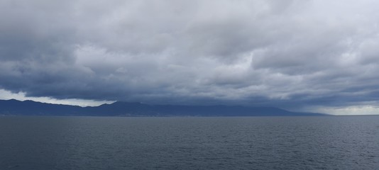 Cloudy day at sea and dark rain clouds on the background of the island