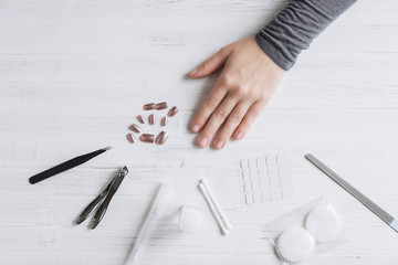 The process of putting artificial (fake) fingernail on the finger. Woman manicure. Flat lay.