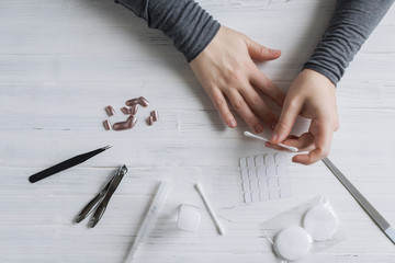 The process of putting artificial (fake) fingernail on the finger. Woman manicure. Flat lay.