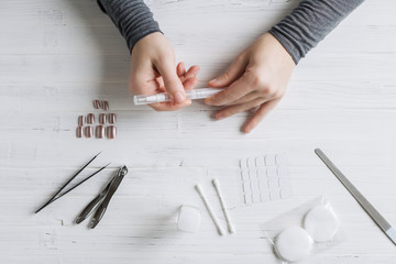 The process of putting artificial (fake) fingernail on the finger. Woman manicure. Flat lay.