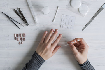 The process of putting artificial (fake) fingernail on the finger. Woman manicure. Flat lay.