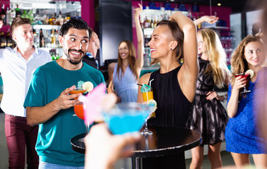 Man with woman are drinking cocktails on corporate party.