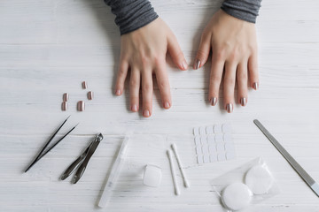 The process of putting artificial (fake) fingernail on the finger. Woman manicure. Flat lay.