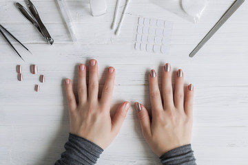 The process of putting artificial (fake) fingernail on the finger. Woman manicure. Flat lay.