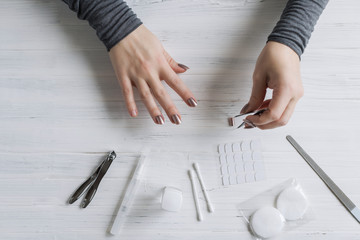 The process of putting artificial (fake) fingernail on the finger. Woman manicure. Flat lay.