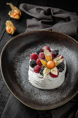 Luxurious dessert. Airy mousse cake made of delicate Bizet with berries decorated with physalis.