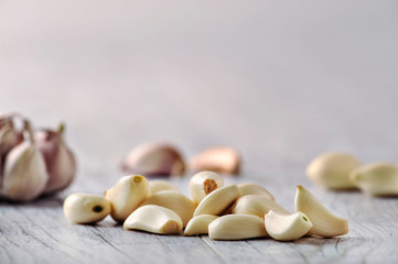 Garlic Cloves and Bulb in wooden bowl on white table.