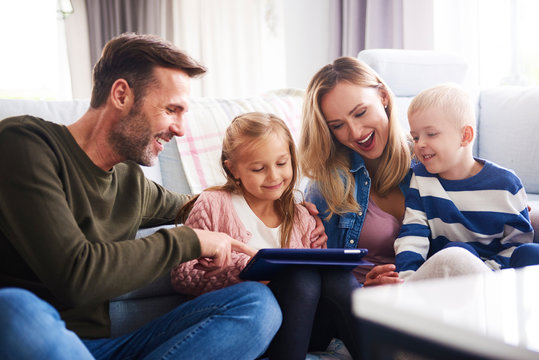 Happy family with tablet spending time together in living room