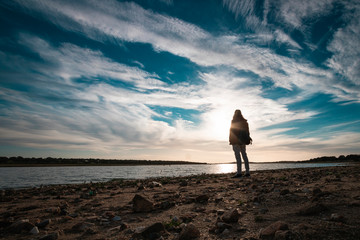 Silueta de un chico al atardecer en un lago