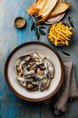 Shellfish Mussels Clams with cheese creamy sauce and French Fries on blue wooden background