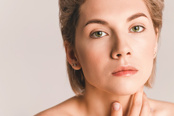 Pretty young woman with beautiful skin and regular facial features in the studio on a light...
