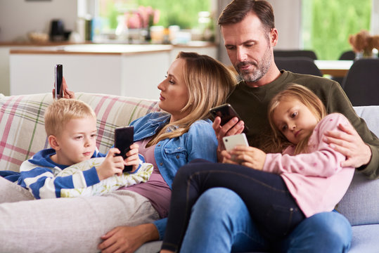 Parents and children using mobile phone in living room