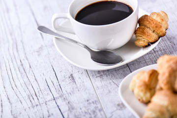 Cup of coffee on wooden tray with croissants.