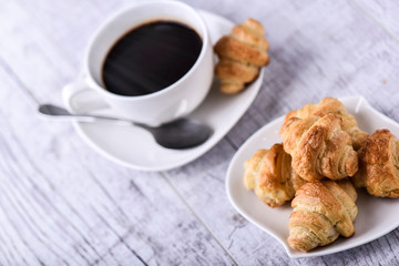 Cup of coffee on wooden tray with croissants.