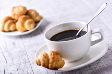 Cup of coffee on wooden tray with croissants.