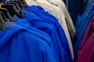 Several rows with top clothes on hangers. View from front.