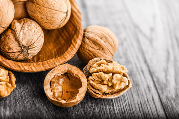 Whole walnuts on dark board, Walnut kernels in wood rustic bowl. Selective focus photo. Helathy food.