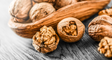 Whole walnuts on dark board, Walnut kernels in wood rustic bowl. raw food.