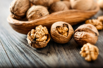 Whole walnuts on dark board, Walnut kernels in wood rustic bowl.