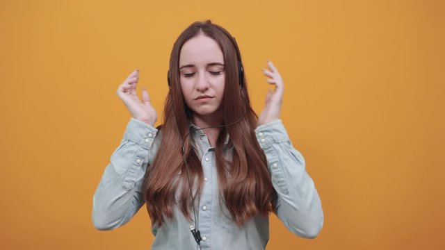 Unhappy attractive caucasian lady wearing fashion shirt isolated on orange background in studio keeping hands crossed on chest, looking at camera. People emotions, lifestyle concept.