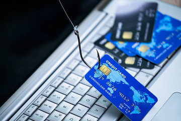 Credit card phishing. Piles of credit cards with a fish hook on computer keyboard. Credit card phishing scam with credit card in fishing hook