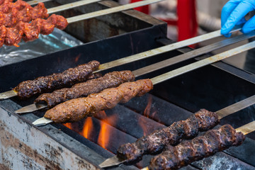 Adana kebab (ground lamb minced meat on skewer on grill over charcoal).Chef preparing traditional authentic Turkish shaworma. Middle eastern cuisine. Handmade specialty street food market with spices