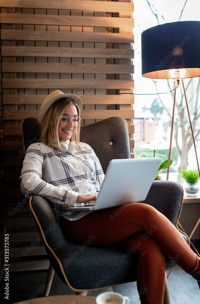 Wall mural Young woman sitting in cafe shop and working on laptop.