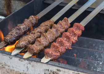 Adana kebab (ground lamb minced meat on skewer on grill over charcoal).Chef preparing traditional authentic Turkish shaworma. Middle eastern cuisine. Handmade specialty street food market with spices