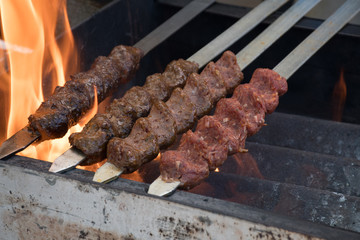 Adana kebab (ground lamb minced meat on skewer on grill over charcoal).Chef preparing traditional authentic Turkish shaworma. Middle eastern cuisine. Handmade specialty street food market with spices