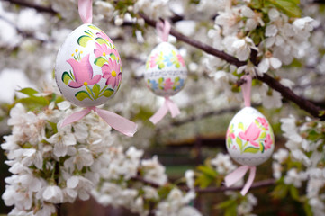 vintage Decorative Easter egg hanging on flowering cherry tree with white flowers. Easter banner background