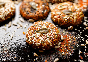 Vegan burgers, baked vegan burgers, cutlets made of carrots, millet, mix of seeds and herbs on dark background, close-up. Healthy eating concept