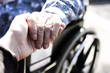 Close up of hands of aged woman sitting in the wheelchair outdoors - 313574586