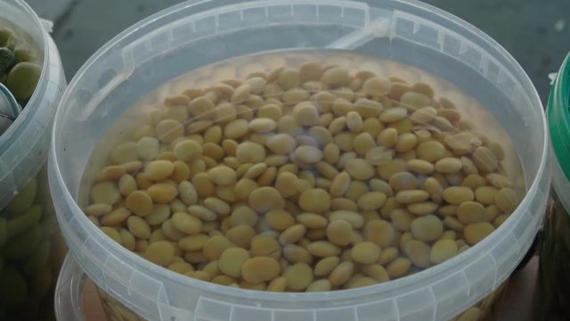 Pickled yellow lupin or lupini beans in bucket at market in Seville, Spain