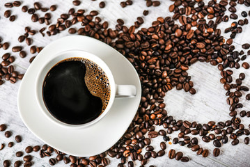 Coffee cup and beans on old white table. Roasted coffee beans top view.