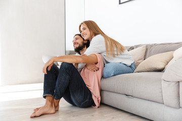 Young loving couple on sofa hugging.