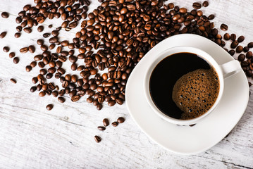 Coffee cup and beans on old white table. Roasted coffee beans top view.