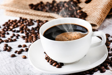 Coffee cup and beans on old white table. Roasted coffee beans top view.
