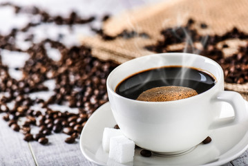 Coffee cup and beans on old white table. Roasted coffee beans top view.