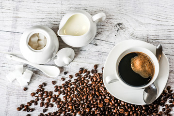 Coffee cup and beans on old white table. Roasted coffee beans top view.
