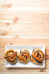 Homemade buns with dark chocolate in a creamic plate with honey on a light wooden background. Copy space top view