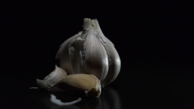 Garlic close-up. whole garlic rotates on a black background. High quality garlic closeup,  rotation. vegetable. onion. 4K UHD video footage 3840X2160