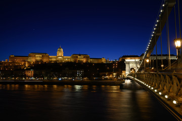 Fototapeta premium Budapest iconic Chain Bridge by night over the Danube River with the Royal Palace and the President's Palace