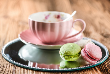 Sweet cake macarons and green tea. Colorful macarons with tea and mint on wooden table.