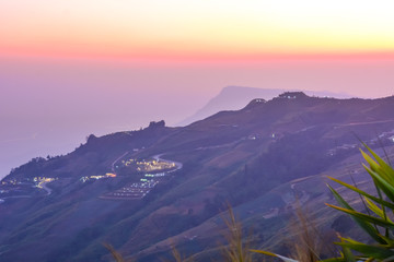 High view beautiful nature landscape of colorful sky during the sunrise, see the lights of the road and city from the campsite at Phu Thap Berk viewpoint, Phetchabun Province, Thailand