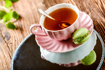 Sweet cake macarons and green tea. Colorful macarons with tea and mint on wooden table.