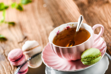 Sweet cake macarons and green tea. Colorful macarons with tea and mint on wooden table.