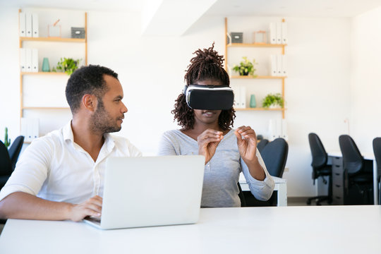 Excited woman testing VR headset with assistant. Cheerful African American young man and woman testing new device. Technology concept - Powered by Adobe